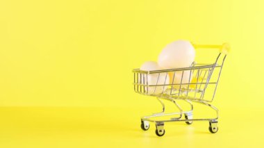 Sarı arka planda yumurtalı alışveriş arabası, yakın plan. Kara Cuma Alışveriş ve İndirim Konsepti.