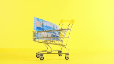 Sarı arka planda 2000 ruble banknotlu alışveriş arabası, yakın plan. Kara Cuma Alışveriş ve İndirim Konsepti