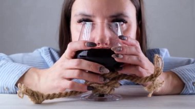 Üzgün kadın şarap kadehi jüt halatla bağlanmış. Alkol bağımlılığı kavramı. Alkolizm tedavisi sorunu