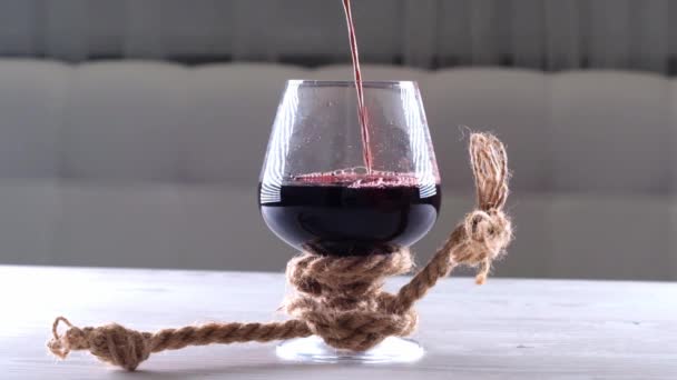 Вино наливают в стакан, связывают веревкой. Концепция алкогольной зависимости. — стоковое видео