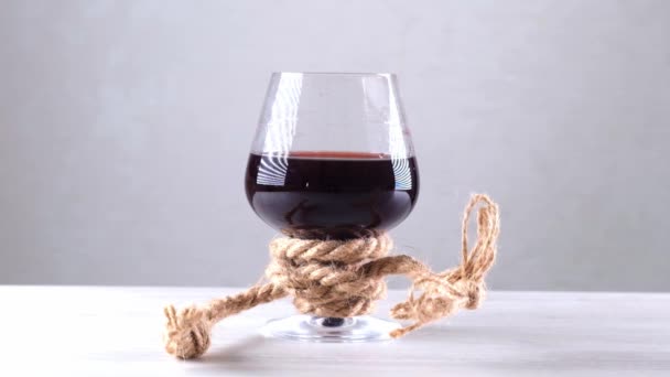 A borospoharat kötéllel kötötték meg. Az alkoholfüggőség fogalma. — Stock videók