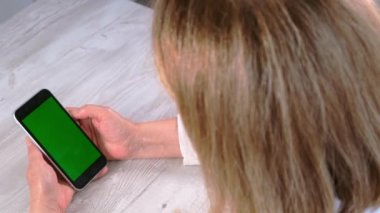 Orta yaşlı bayan sinyora krom ekranlı iPhone akıllı telefonu kullanıyor, fotokopi alanı, üst görünüm. Çevrimiçi alışveriş kavramı, mobil uygulamaların kullanımı: Moskova, Rusya - 24 Haziran 2021.