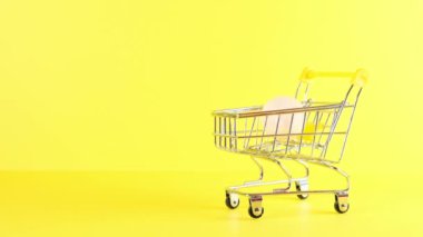 Sarı arka planda yumurtalı alışveriş arabası, yakın plan. Kara Cuma Alışveriş ve İndirim Konsepti.