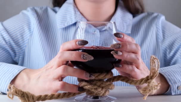 Manos femeninas sosteniendo copa de vino está atado con una cuerda de yute. El concepto de dependencia al alcohol. El problema del tratamiento del alcoholismo — Vídeos de Stock