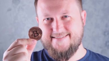 Elinde altın bir bitcoin tutan sakallı zengin bir adamın portresi. Madencilik, kripto para birimi, madencilik ve elektronik parayla yerleşim.