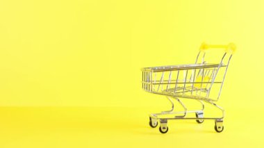 Sarı arka planda boş bir alışveriş arabası, yakın plan. Kara Cuma Alışveriş ve İndirim Konsepti