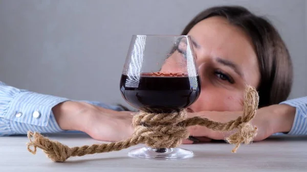 Triste mujer mirando copa de vino atado con cuerda de yute. El concepto de adicción al alcohol. El problema del tratamiento del alcoholismo — Foto de Stock