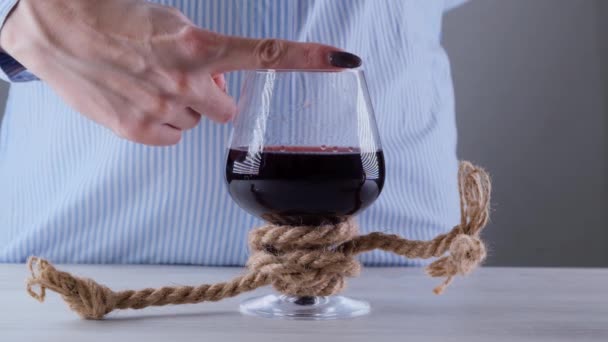 Kadın eli, "Olmaz" işaretini gösterir, şarap kadehinde durur, jüt bir iple bağlanır. Alkol bağımlılığı kavramı. Alkolizm tedavisi sorunu — Stok video