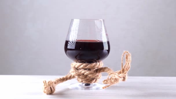 La copa de vino está atada con una cuerda. El concepto de dependencia del alcohol. — Vídeo de stock