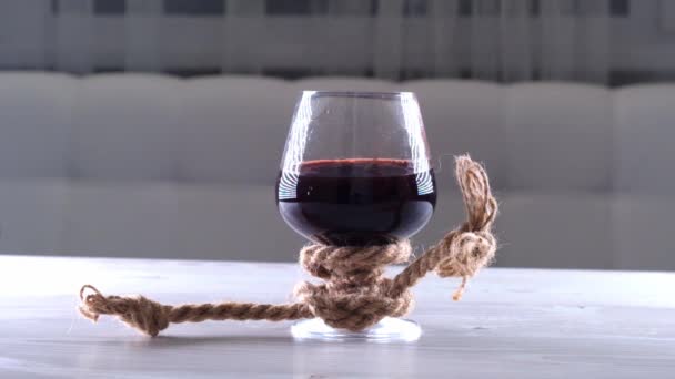 Le verre à vin est attaché avec une corde. Le concept de dépendance à l'alcool. — Video