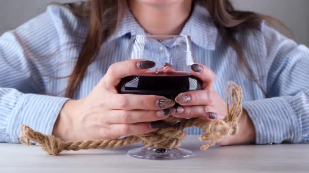 手里拿着酒杯的女手用黄麻绳绑着。酒精依赖的概念。酗酒治疗的问题 — 图库视频影像