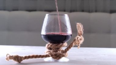 Şarap bardağa dökülür ve bir iple bağlanır. Alkol bağımlılığı kavramı.