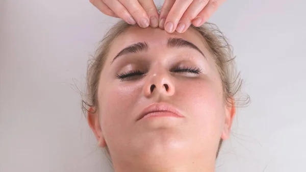 Facial massage beauty treatment. Close up of a young womans face lying on back, getting face lifting massage, pinch and roll technique — Stock Photo, Image