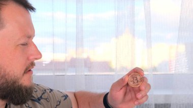 Elinde altın bir bitcoin tutan bir adamın portresi. Madencilik, kripto para birimi, madencilik ve elektronik parayla yerleşim.