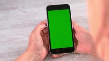 Orta yaşlı kadınlardan yeni normal konseptte ulaşılamıyor ve yeşil ekranlı akıllı telefon kullanılıyor: Moskova, Rusya - 24 Haziran 2021.