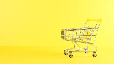 Sarı arka planda boş bir alışveriş arabası, yakın plan. Kara Cuma Alışveriş ve İndirim Konsepti