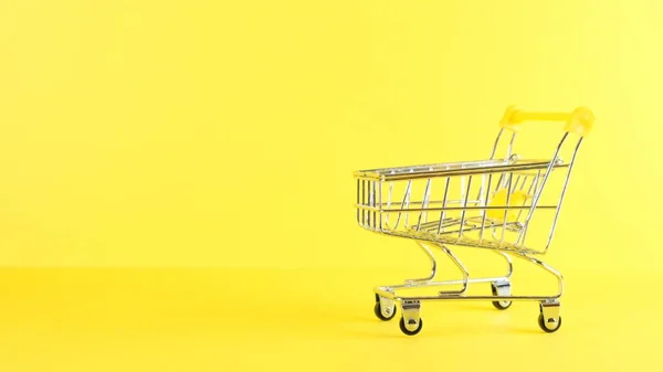 Vacío carrito de compras sobre un fondo amarillo, primer plano. Viernes Negro Compras y descuento Concepto — Foto de Stock