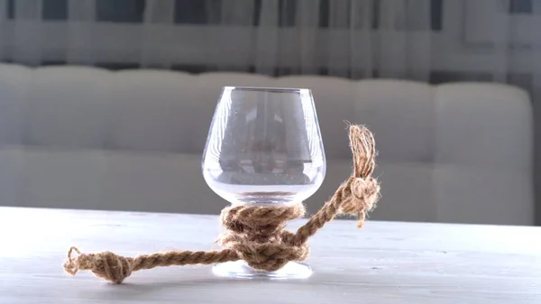 空のワイングラスは正しいロープで結ばれている。アルコール依存の概念. — ストック写真