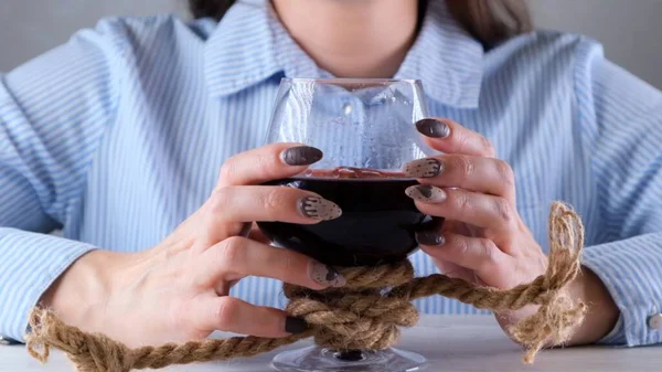 Manos femeninas sosteniendo copa de vino está atado con una cuerda de yute. El concepto de dependencia al alcohol. El problema del tratamiento del alcoholismo — Foto de Stock