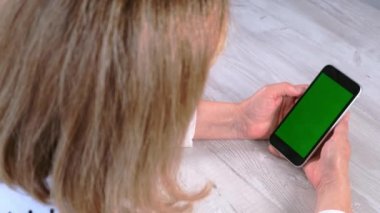 Orta yaşlı bayan sinyora krom ekranlı iPhone akıllı telefonu kullanıyor, fotokopi alanı, üst görünüm. Çevrimiçi alışveriş kavramı, mobil uygulamaların kullanımı: Moskova, Rusya - 24 Haziran 2021.