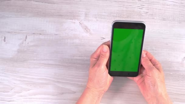 Handen van een vrouw van middelbare leeftijd senior maakt gebruik van een smartphone iPhone met een chroma key screen, kopieer ruimte. Online shopping concept, gebruik van mobiele applicaties: Moskou, Rusland - 24 juni 2021. — Stockvideo