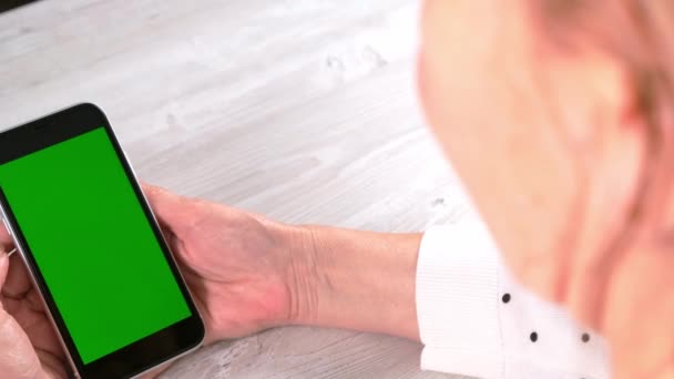 中年女性Senora使用带有彩色按键屏幕的iPhone智能手机，复制空间。在线购物概念，移动应用程序的使用：2021年6月24日，俄罗斯莫斯科. — 图库视频影像