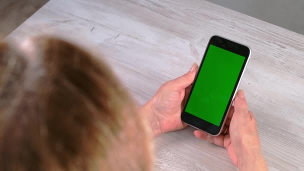 Η μεσήλικη σενιόρα χρησιμοποιεί ένα iPhone smartphone με χρωματική οθόνη κλειδιού, χώρο αντιγραφής, κορυφαία προβολή. Online εμπορική ιδέα, χρήση εφαρμογών για κινητά: Μόσχα, Ρωσία - 24 Ιουνίου 2021. — Αρχείο Βίντεο