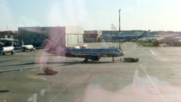 Avión estacionado en el aeropuerto de Moscú a través de la ventana de la puerta. Mantenimiento y preparación del avión para el regimiento: Moscú, Rusia - 28 de junio de 2021. — Vídeo de stock