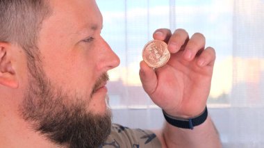 Elinde altın bir bitcoin tutan bir adamın portresi. Madencilik, kripto para birimi, madencilik ve elektronik parayla yerleşim.