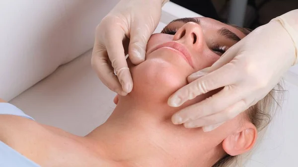 Massage du menton de femme jeune femme pendant le massage du visage au salon de beauté — Photo