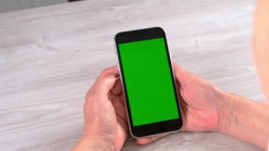 Orta yaşlı kadınlardan yeni normal konseptte ulaşılamıyor ve yeşil ekranlı akıllı telefon kullanılıyor: Moskova, Rusya - 24 Haziran 2021.