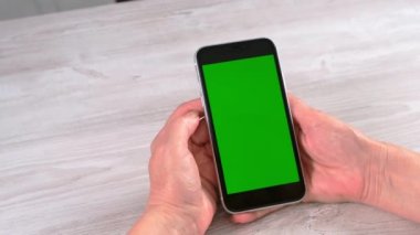 Orta yaşlı kadınlardan yeni normal konseptte ulaşılamıyor ve yeşil ekranlı akıllı telefon kullanılıyor: Moskova, Rusya - 24 Haziran 2021.