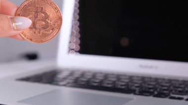 Kadın eli Altın Kripto Para Birimi Bitcoin ve Defter 'i tutuyor. Laptop ve Cyrptocurrency Bitcoin Bilgisayar bulanıklığı. para işi dijital konsept.