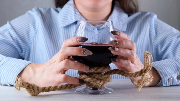 Mãos femininas segurando copo de vinho é amarrado com uma corda de juta. O conceito de dependência de álcool. O problema do tratamento do alcoolismo — Fotografia de Stock