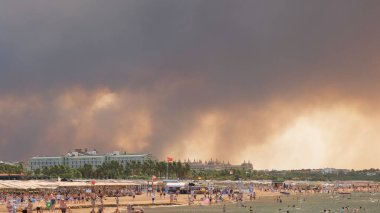 Türkiye 'nin Manavgat tatil beldesi Antalya' da bir plajda orman yangınlarından çıkan duman. Sahilde insanlarla görüntüleme: Antalya, Manavgat Turkey - 28 Temmuz 2021.