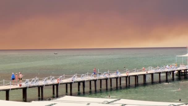 Дим від лісових пожеж здіймається над узбережжям в Анталії, Манавгат курортного міста Туреччини. Вид з людьми на пляжі: Анталія, Манавгат Туреччина - 28 липня 2021 року. — стокове відео