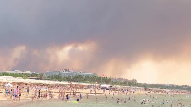 Fumaça de incêndios florestais subindo sobre uma praia em Antalya, cidade turística de Manavgat. Vista com as pessoas na praia: Antalya, Manavgat Turquia - 28 de julho de 2021. — Vídeo de Stock
