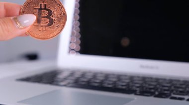 Kadın eli Altın Kripto Para Birimi Bitcoin ve Defter 'i tutuyor. Laptop ve Cyrptocurrency Bitcoin Bilgisayar bulanıklığı. para işi dijital konsept.
