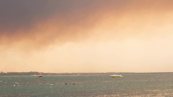 Rauch von Waldbränden steigt über einem Meer im türkischen Badeort Antalya auf. Aussicht mit Menschen am Strand: Antalya, Manavgat Türkei - 28. Juli 2021. — Stockvideo