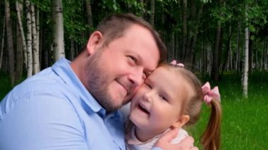 Parkta yürürken mutlu baba-kız kucaklaşan bir çiftin portresi.