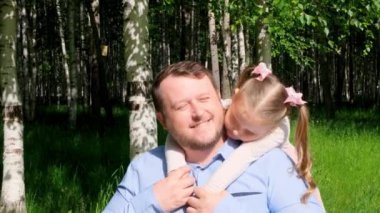 Parkta yürürken mutlu baba-kız kucaklaşan bir çiftin portresi.