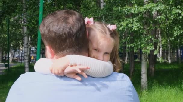 Parkta yürürken 4-5 yaşındaki kızını kucağında taşıyan mutlu bir baba. — Stok video