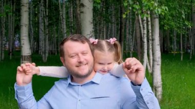 Neşeli baba-kız 3-4 yaşlarındayken parkta yürürken sarılıp oynaşıyorlar.