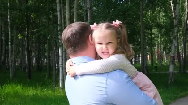 Boldog apa cipeli a nyakában, és megöleli lánya 4-5 éves, miközben sétál a parkban — Stock videók