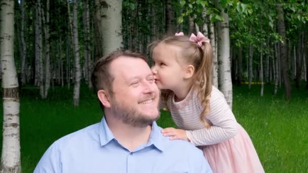 3 살된 귀여운 딸 이 아빠에게 귓속말로 웃는다. 행복 한 어린 시절, 아버지가 되는 것, 육아라는 개념. 부모와 자녀 사이의 신뢰하는 관계. 아버지들의 날 — 비디오
