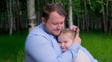 Gülümseyen baba, 3 yaşındaki küçük kızına nazikçe sarılıyor ve babalığının tadını çıkarıyor. Babalar Günü. Mutlu çocukluk ve ebeveynlik kavramları. Çocuk koruması