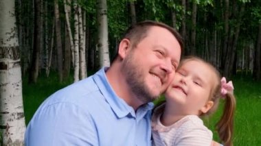 Gülümseyen baba, 3 yaşındaki küçük kızına nazikçe sarılıyor ve babalığının tadını çıkarıyor. Babalar Günü. Mutlu çocukluk ve ebeveynlik kavramları. Çocuk koruması