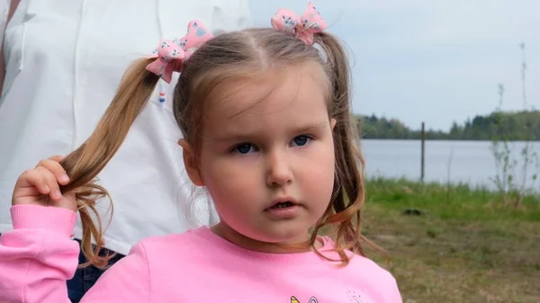 Retrato de uma linda menina de 3 anos, vestida com uma camisola rosa com dois rabos de cavalo, brincando ao ar livre na natureza. Conceito de infância feliz, desenvolvimento infantil — Fotografia de Stock