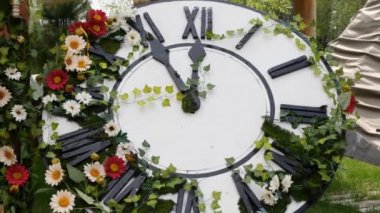 Sahada çiçek açan büyük duvar saati, saati 11: 55, 12: 00 gösteriyor. Zaman yönetimi kavramı, gün ışığı tasarrufu. Bahar ya da düğün. Kadınlar için piknik günü