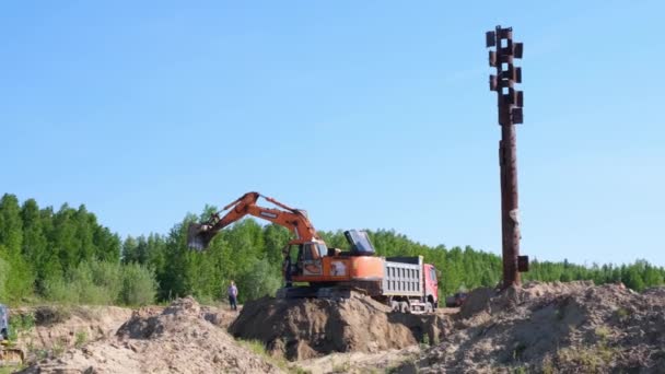 La excavadora amarilla realiza trabajos de tierra excavando arena en un sitio de construcción: Moscú, Rusia - 30 de agosto de 2021. — Vídeo de stock
